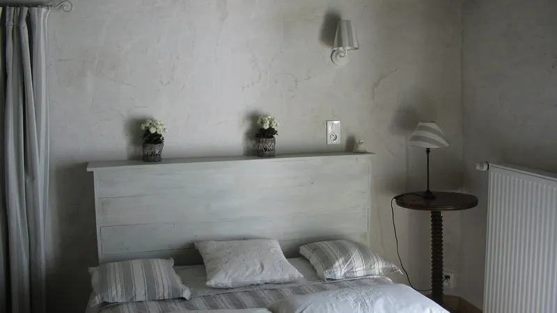 Chambre avec lit double, tête de lit peinte en blanc, bouquets de fleurs et lampe de chevet