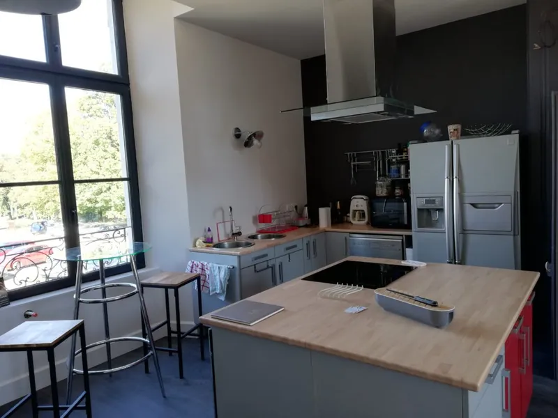 Cuisine ouverte avec îlot central en bois, plaques de cuisson et grand réfrigérateur américain