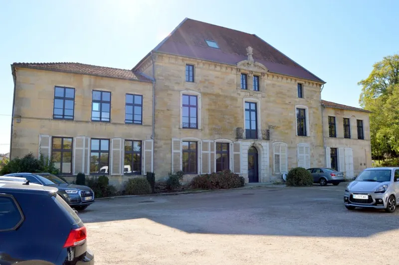 Façade en pierre du château du XVIe siècle abritant le gîte, avec parking gravillonné devant l'entrée
