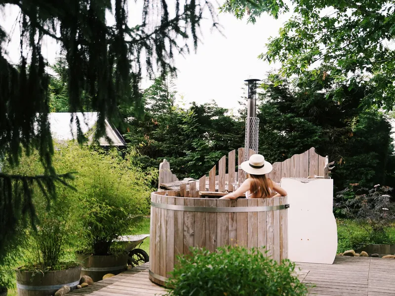 Bain nordique en bois chauffé au feu, installé sur une terrasse entourée d'arbres