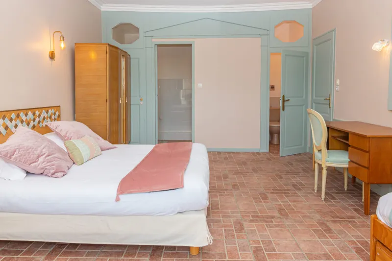 Chambre double aux tons rose poudré et vert d'eau, grand lit et fenêtre donnant sur le parc