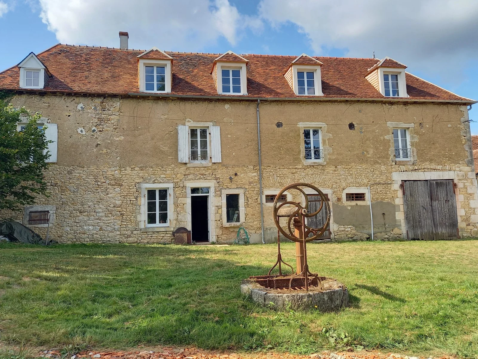 Gîte de groupe Les Fonteneilles à Bouesse — Façade en pierre du corps de logis avec quatre lucarnes sur toit de tuiles et grande pelouse, capacité 38 personnes