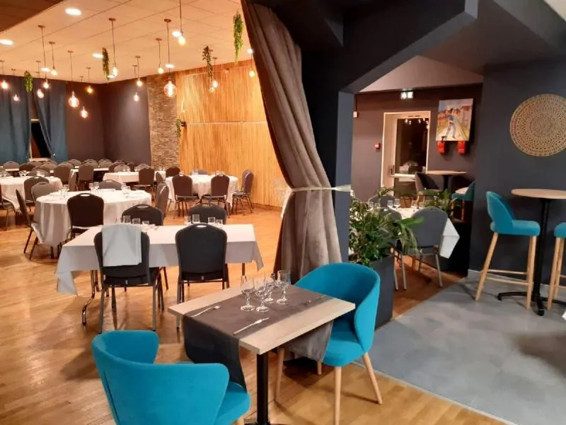 Grande salle de réception avec tables rondes dressées de nappes blanches et chaises sombres