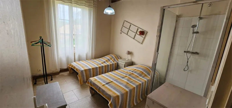 Chambre twin avec lits rayés jaunes, douche intégrée et grande fenêtre