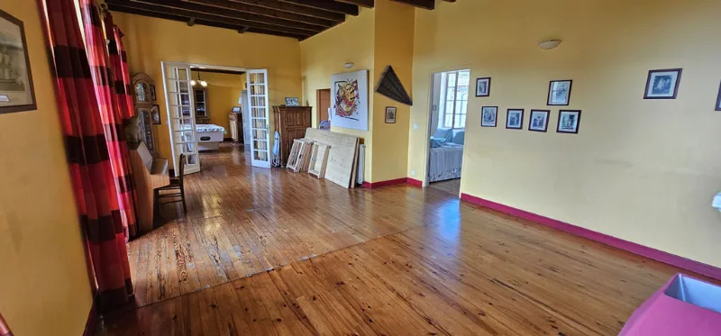 Grande salle lumineuse avec parquet en bois et œuvres d'art accrochées