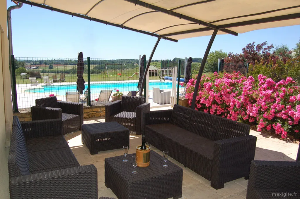 Terrasse ombragée avec salon de jardin et vue sur la piscine chauffée du domaine
