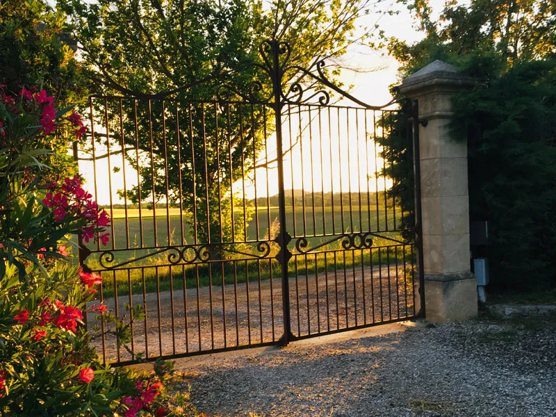 Entrée du Domaine d'Engrazac avec allée bordée de verdure et façade en pierre