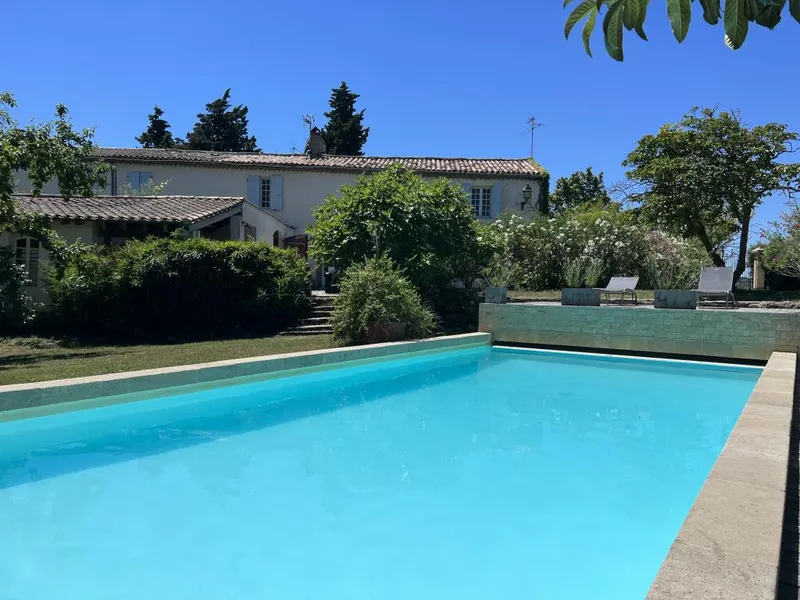Facade en pierre des gites La Chouette Bleue vue depuis la piscine chauffee avec jardin arbore