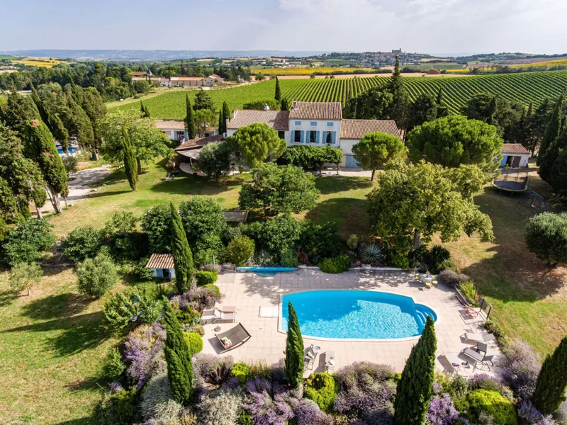 Vue aerienne du Domaine de Segonne avec la maison aux volets bleus, la piscine, les jardins et les vignes du Pays Cathare en arriere-plan