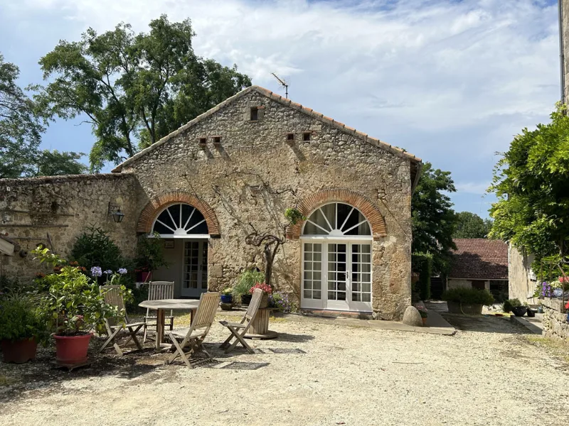 Grange en pierre rénovée avec terrasse bois et table de jardin ombragée
