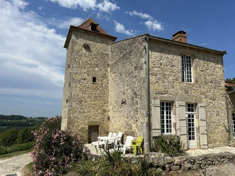 Tour en pierre ancienne avec terrasse et chaises blanches, vue dégagée